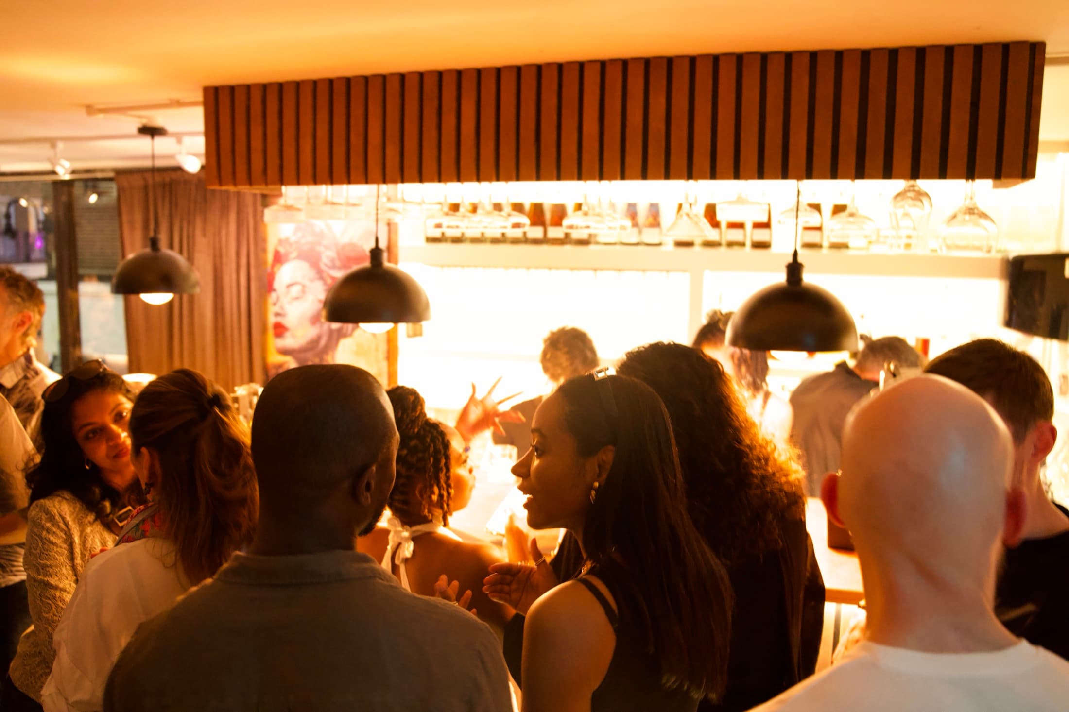 The room filling up in front of the back bar, glassware racked above the counter