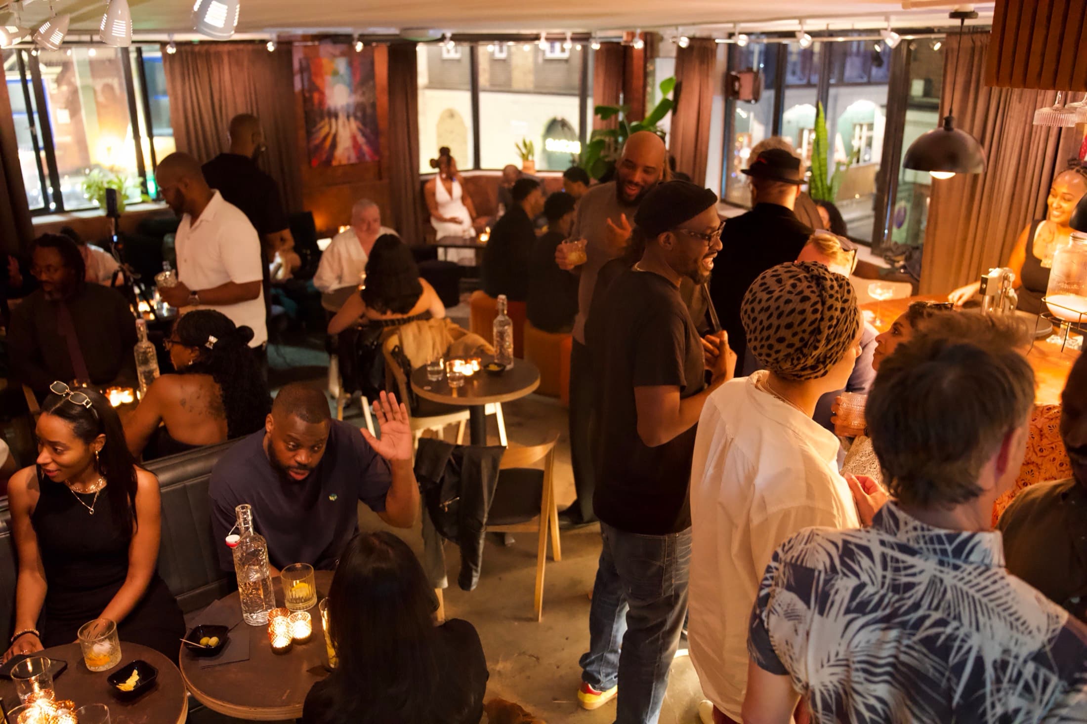 A full room on a Friday night at the BCC Bar — guests standing and seated around the tables, candles and rum bottles on every table