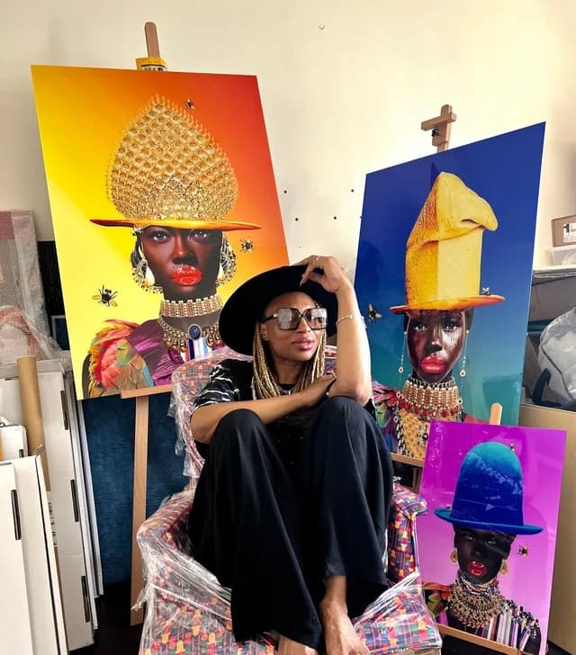 Caroline Chinakwe in her studio, sitting in front of three of her large portrait works