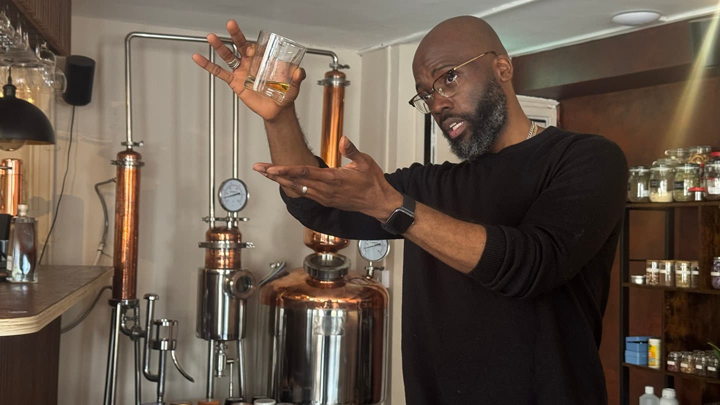 Your host holding a glass of rum mid-story in front of the copper stills