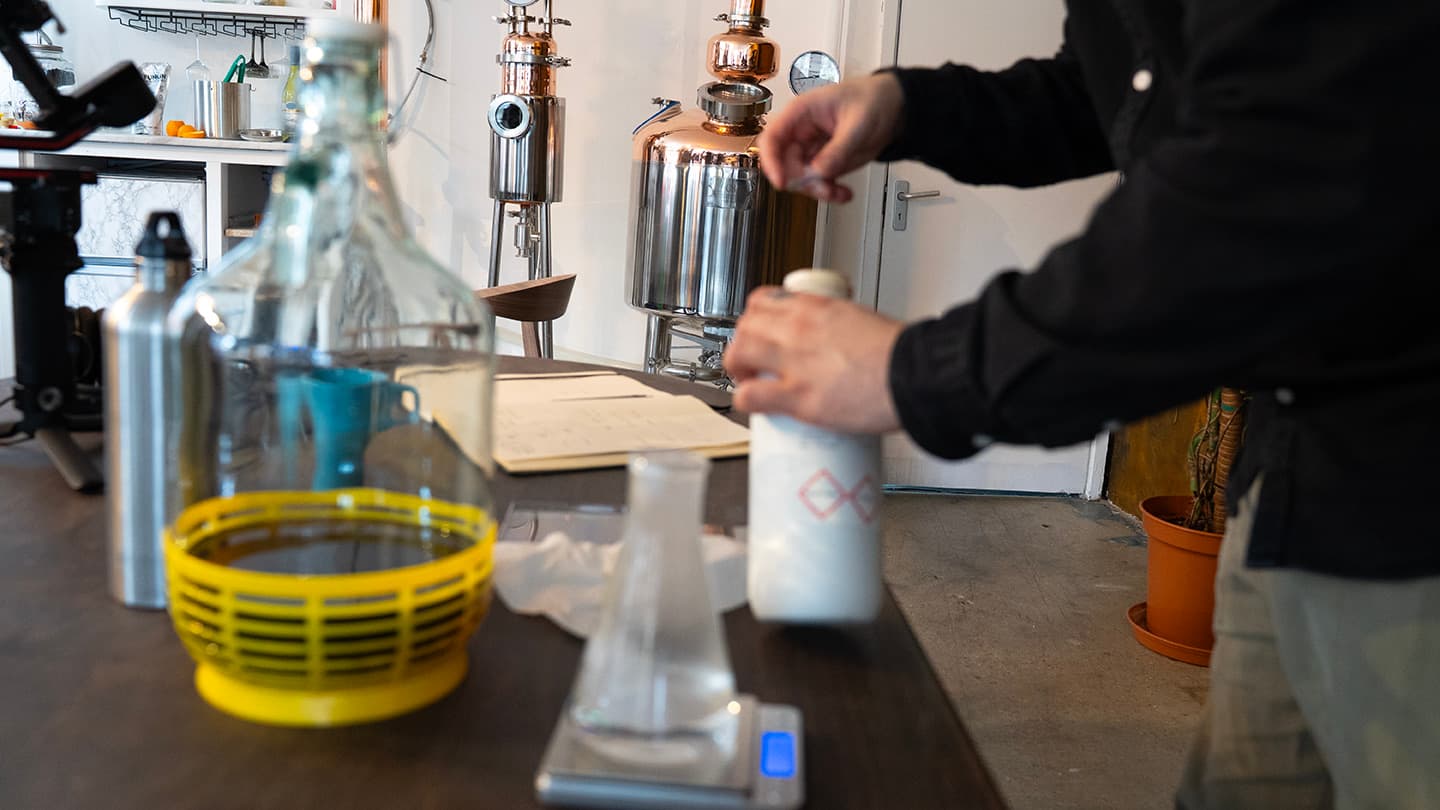 Weighing botanicals on the scales beside the copper stills before charging them