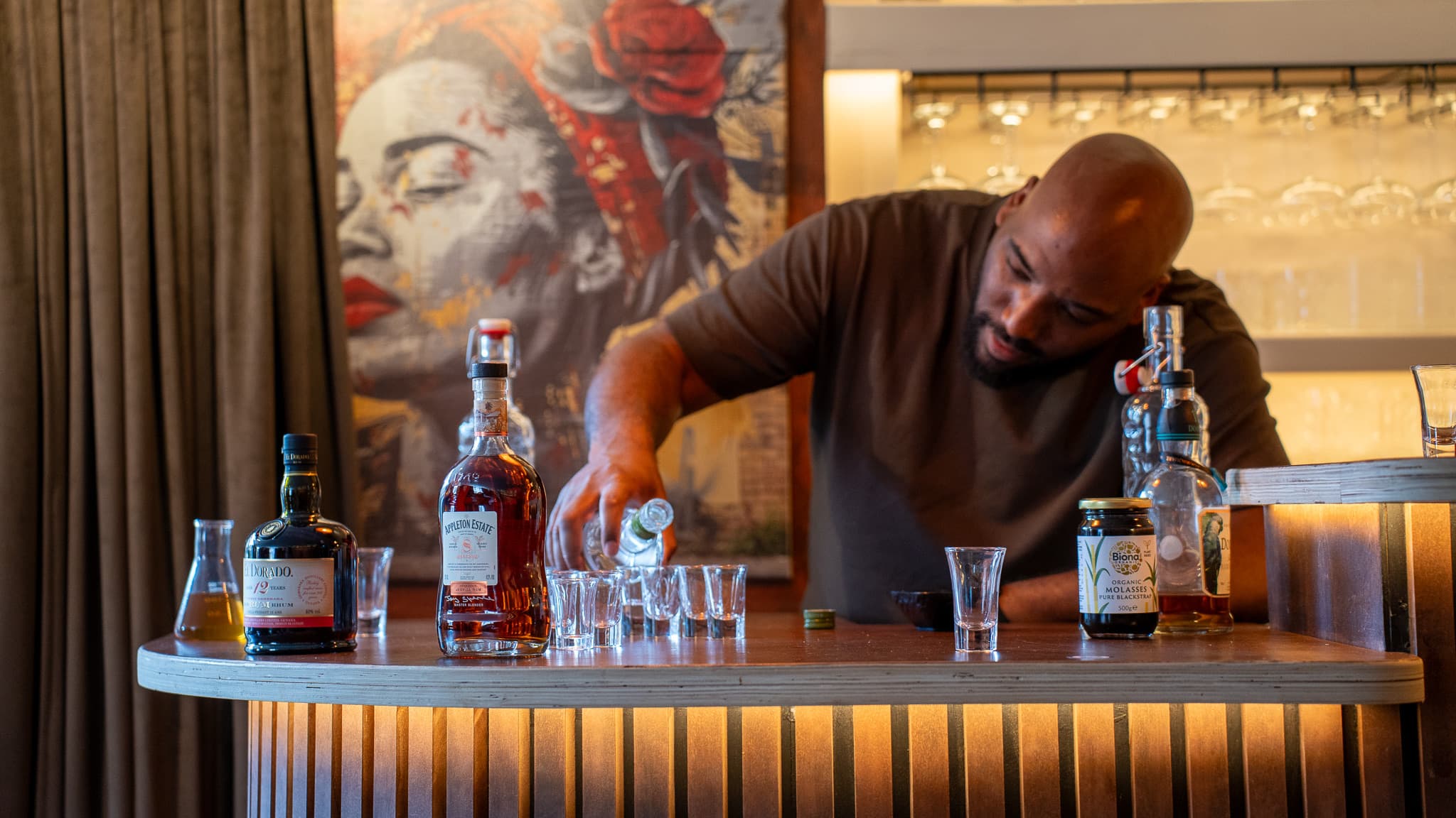 The host pouring the next rum at the bar, bottles lined up beside him