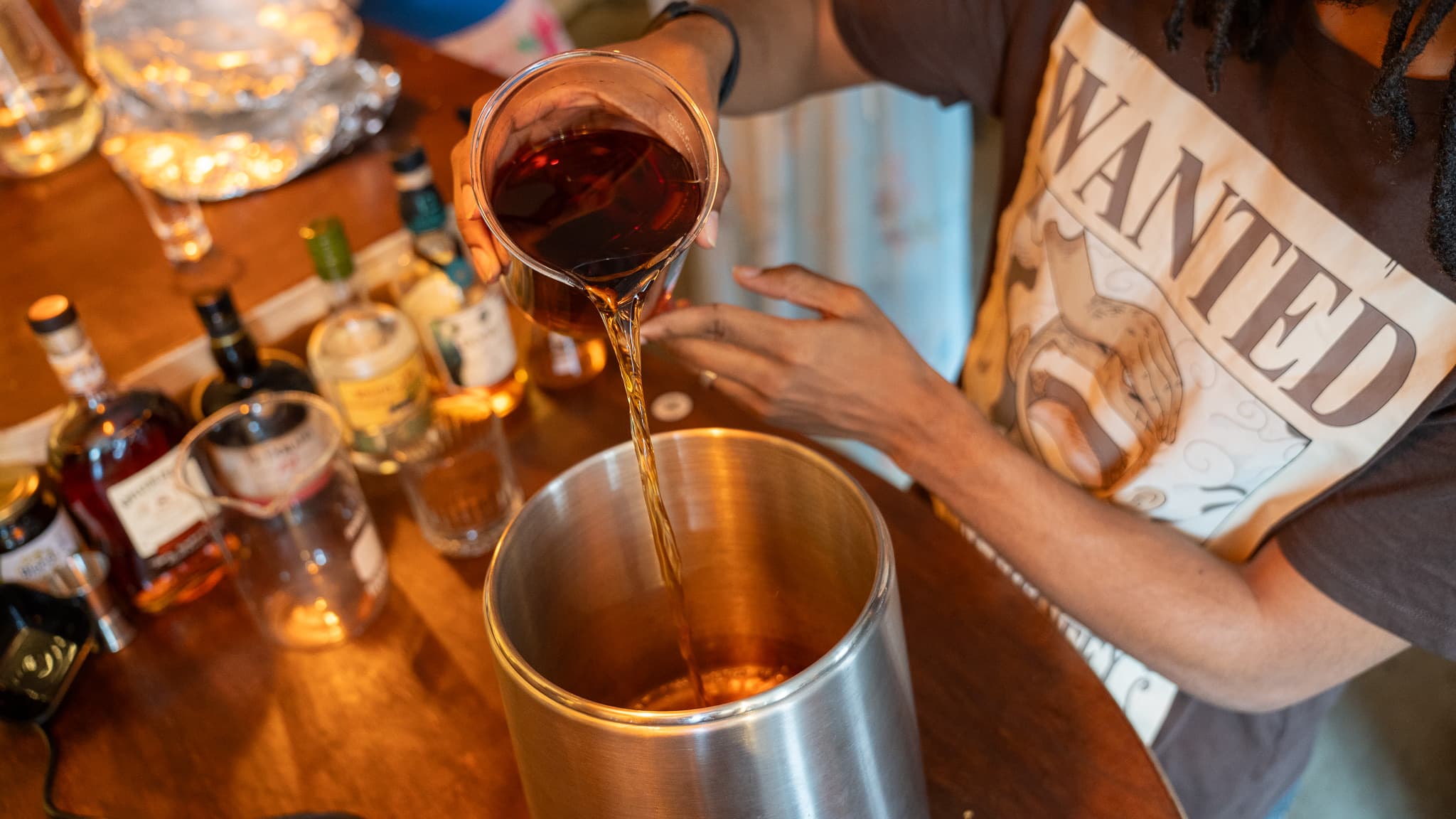 Rum poured from a jug into a steel pot on the bar