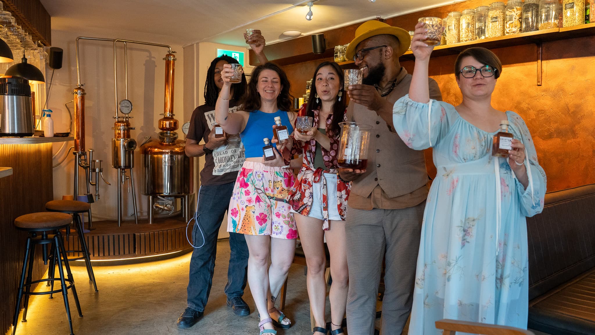 The group raising their glasses in front of the copper stills at the end of the tasting